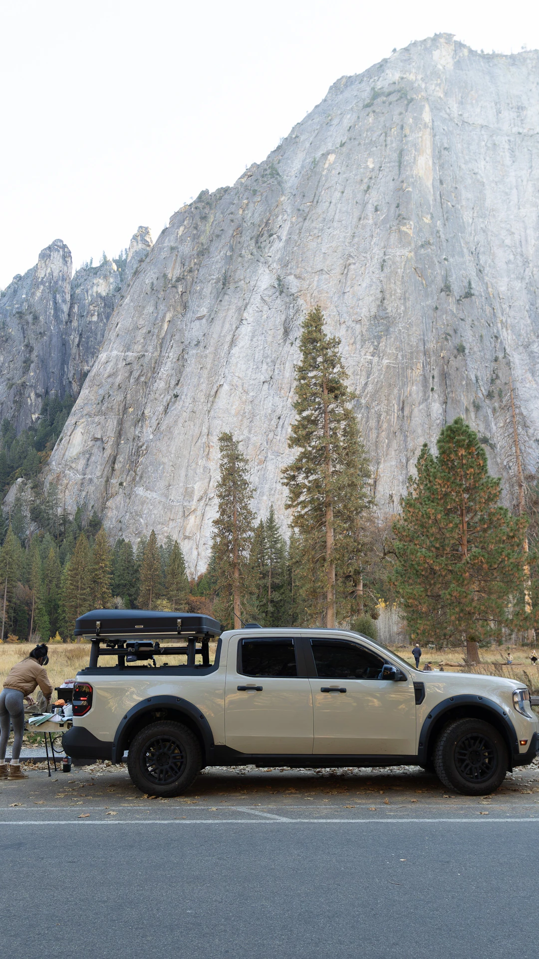 Person setting up camp next to truck with mountain backdrop