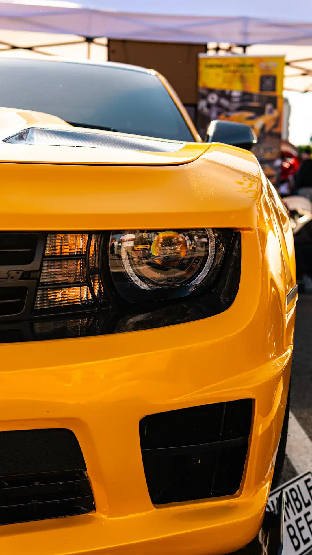 Yellow sports car's front grille and headlight.