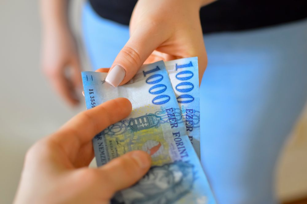 An exchange of 1000 Hungarian Forint banknotes between two hands.