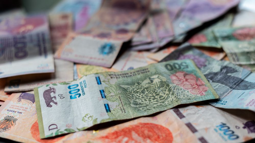 A detailed view of Argentine peso banknotes scattered on a table, showcasing various denominations.