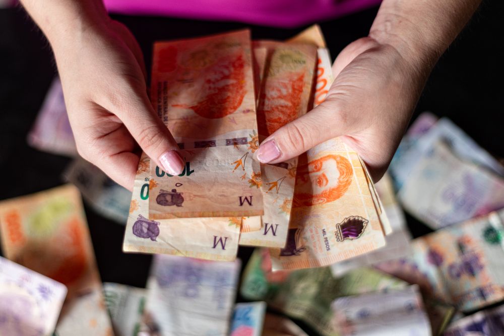 Hands holding Argentine peso notes, representing currency and finance in Buenos Aires, Argentina.