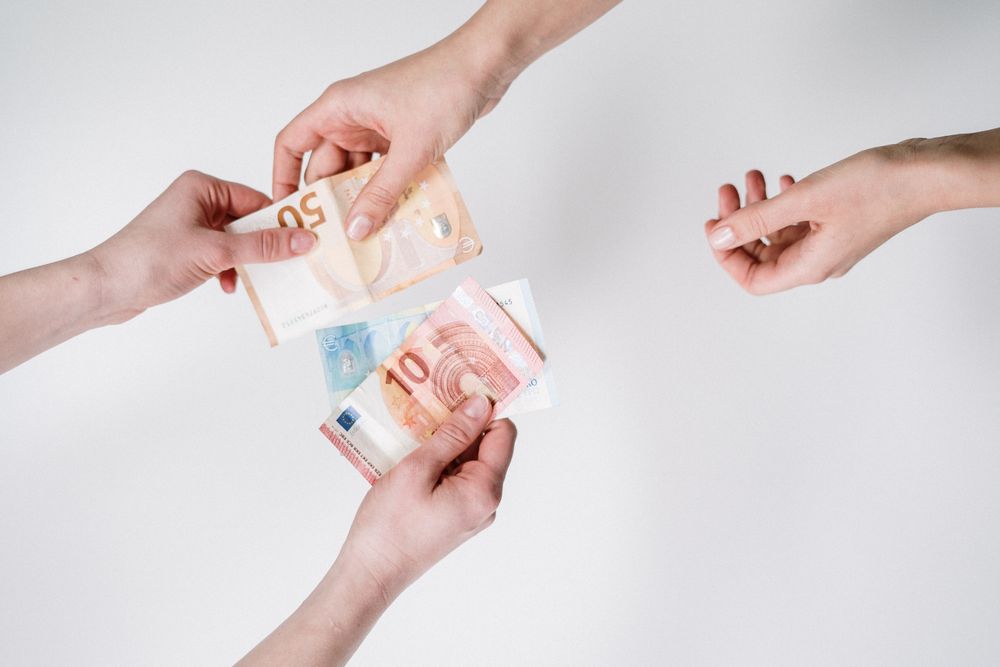 Close-up of hands exchanging euro banknotes, symbolizing currency trade and financial transactions.