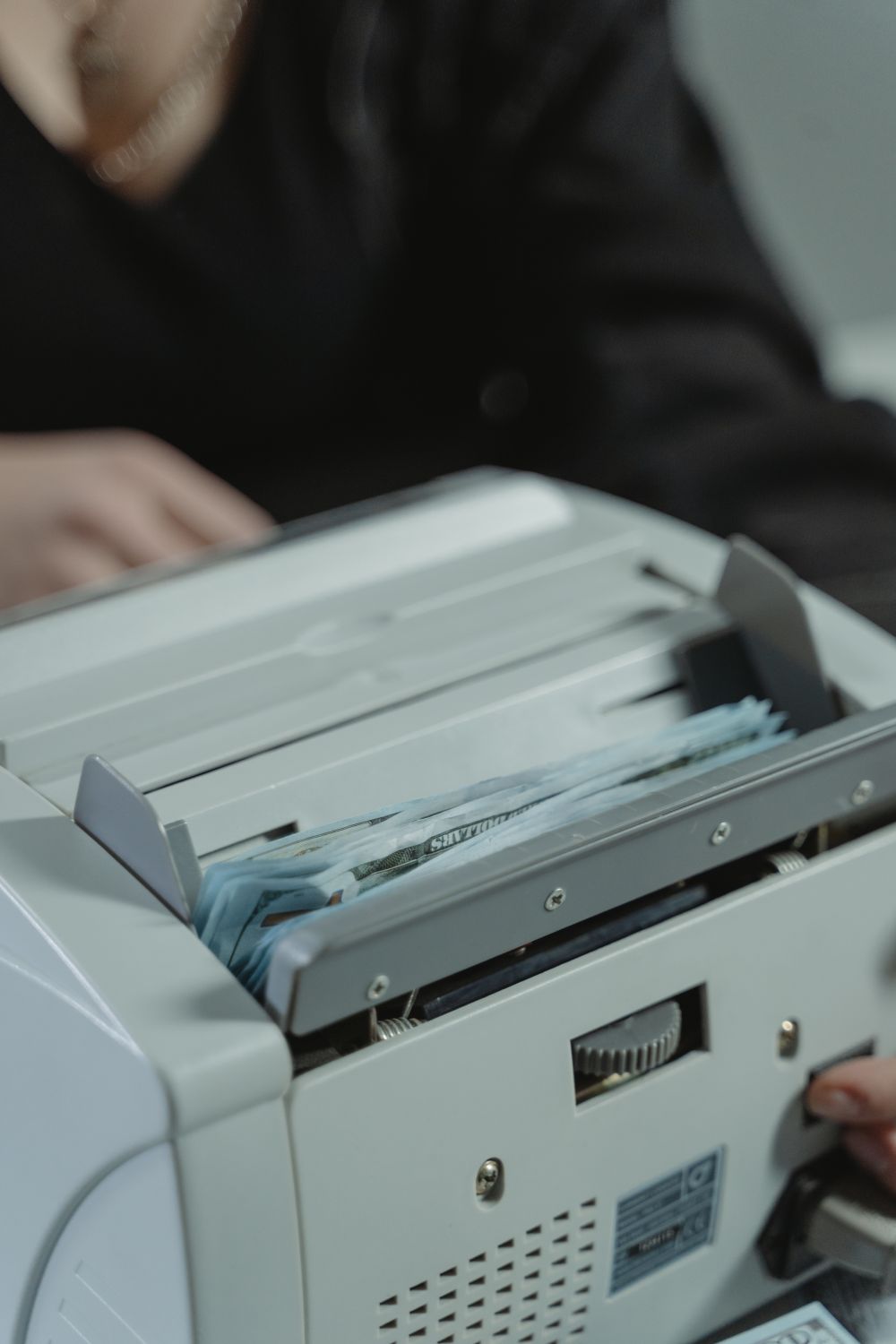 Close-up shot of a money counting machine with bills being processed indoors.