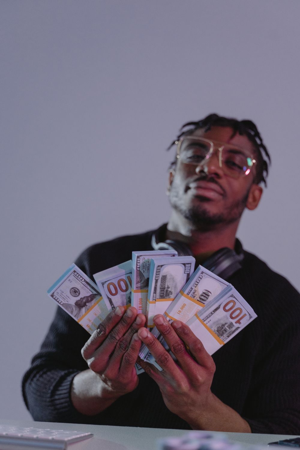 African American man holding bundles of banknotes indoors with a confident expression.