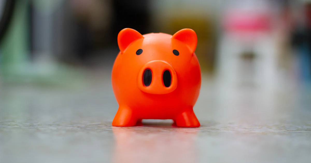 A small orange piggy bank sits on a surface